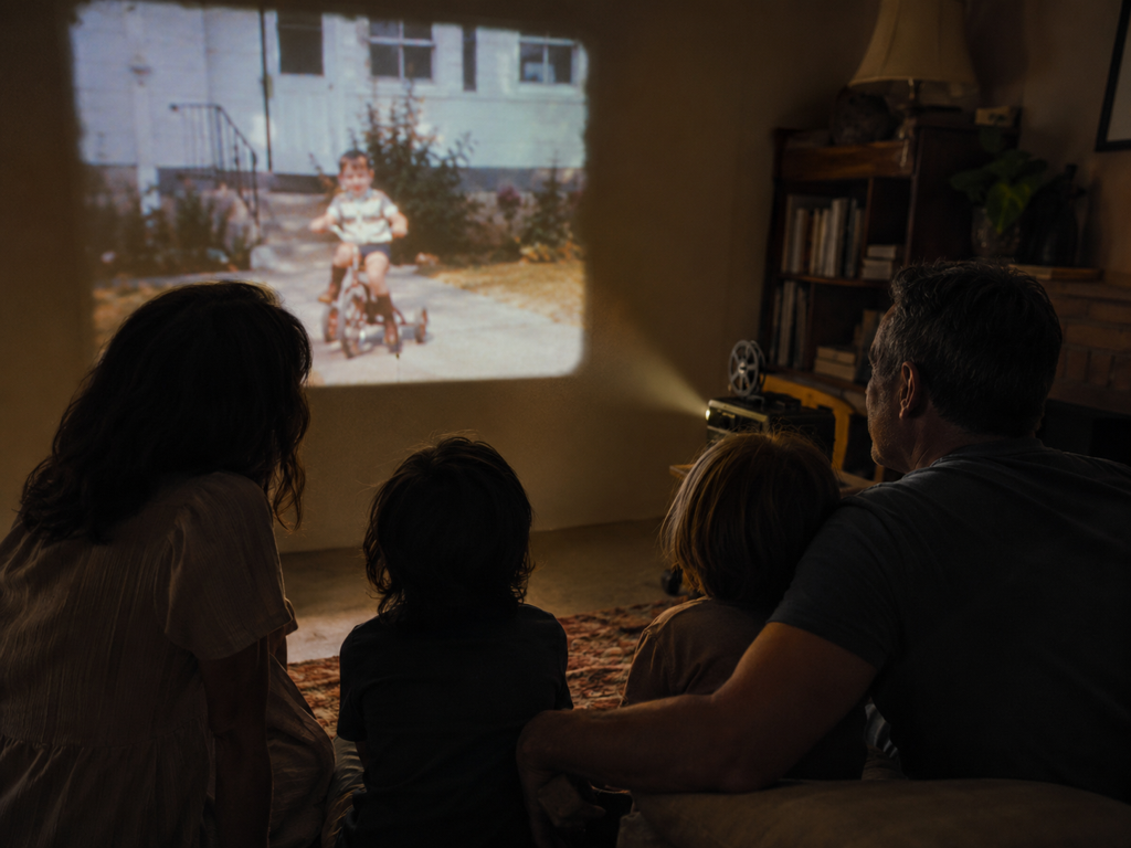 A family watching a restored DV era home movie on a large living room screen